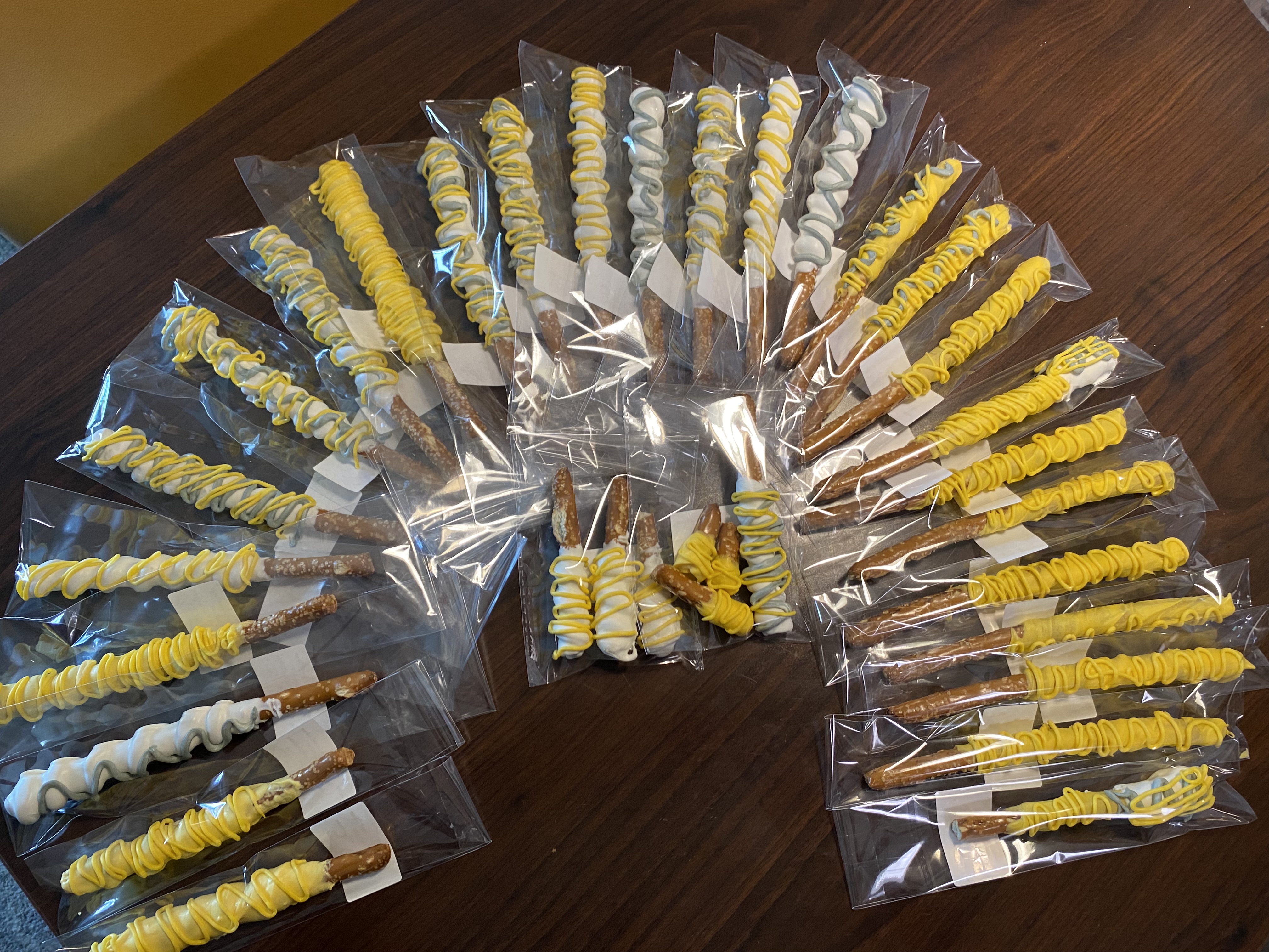 Chocolate-dipped pretzel rods decorated in yellow and white