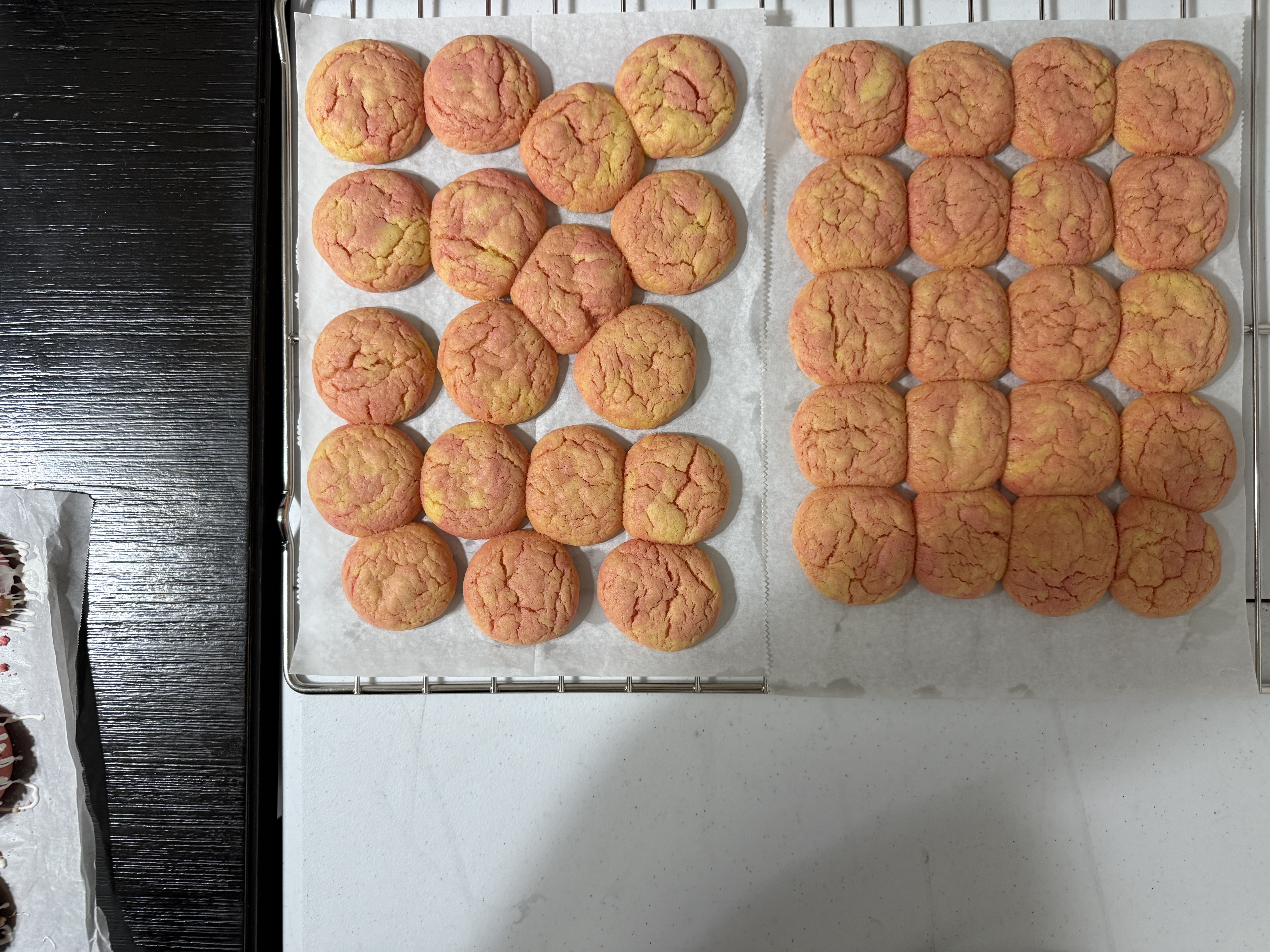 A batch of soft pink and golden cookies cooling